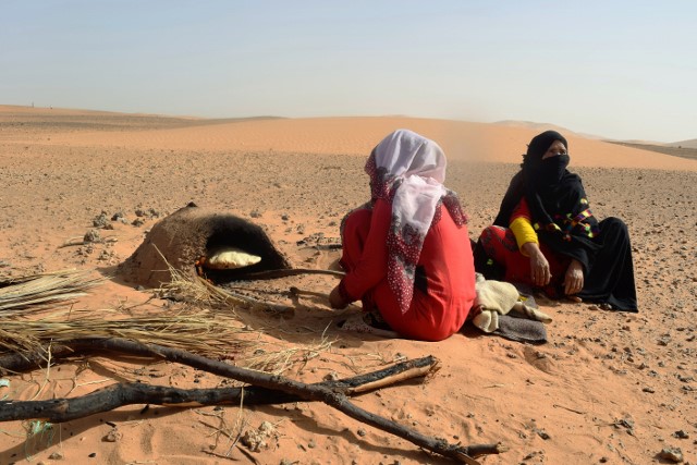 Nomadic women bake stuffed bread in the oven just outside their tent.