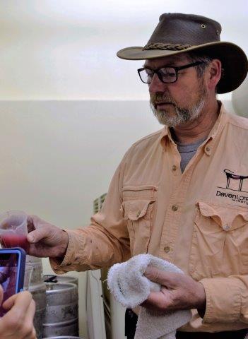 DavenLore's Gordon Taylor shares samples of day-old pressed grape juice from a fermenting bin.